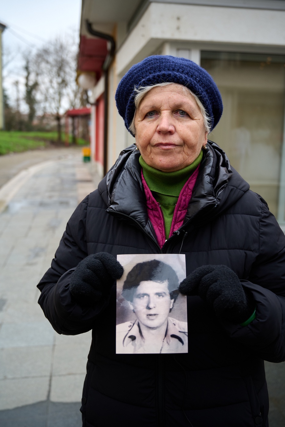 Шугра Ахметович на місці вбивства свого брата тримає його фотографію.